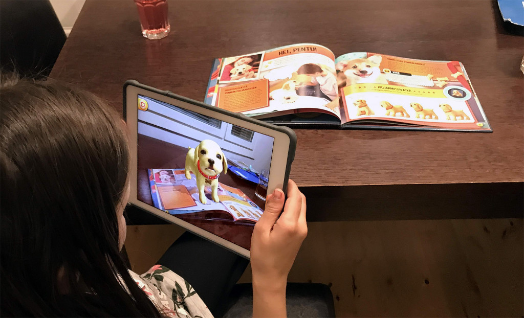 A kid with an iPad watching a book with augmented content